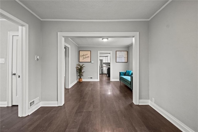 hallway with a textured ceiling, ornamental molding, and dark wood-type flooring