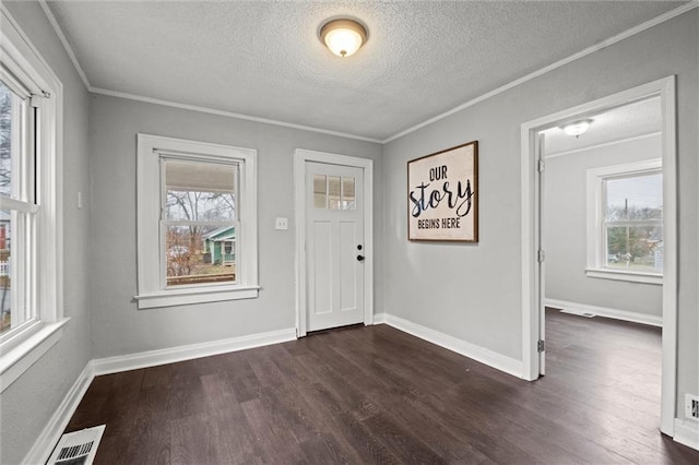 entrance foyer with a healthy amount of sunlight, dark hardwood / wood-style floors, and ornamental molding