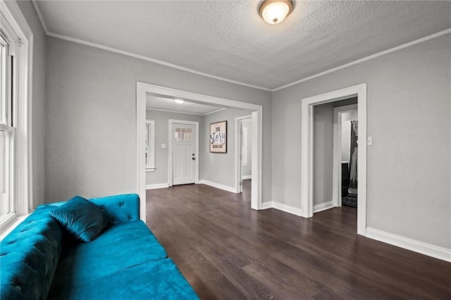 unfurnished living room featuring a wealth of natural light, dark wood-type flooring, a textured ceiling, and ornamental molding