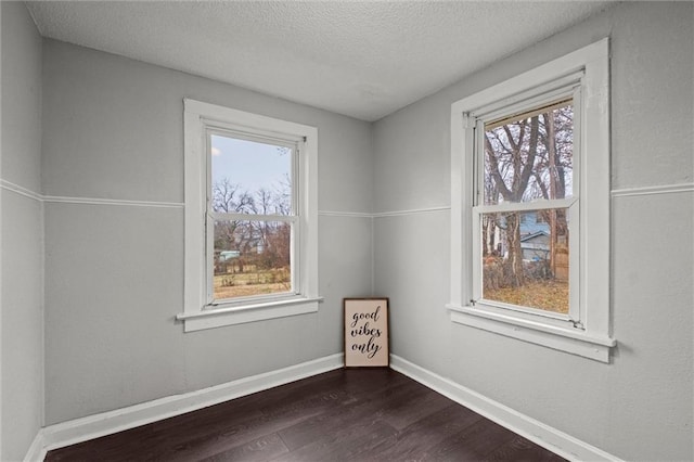 unfurnished room with a textured ceiling and dark hardwood / wood-style floors