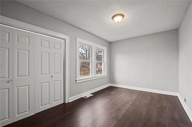 unfurnished bedroom featuring dark wood-type flooring, a textured ceiling, and a closet