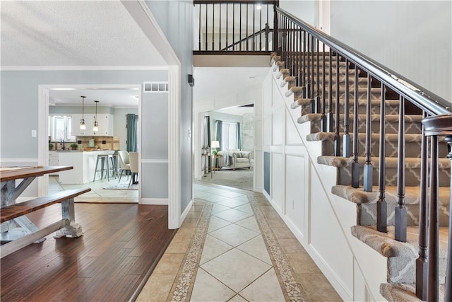 foyer entrance with sink, light tile patterned floors, and ornamental molding