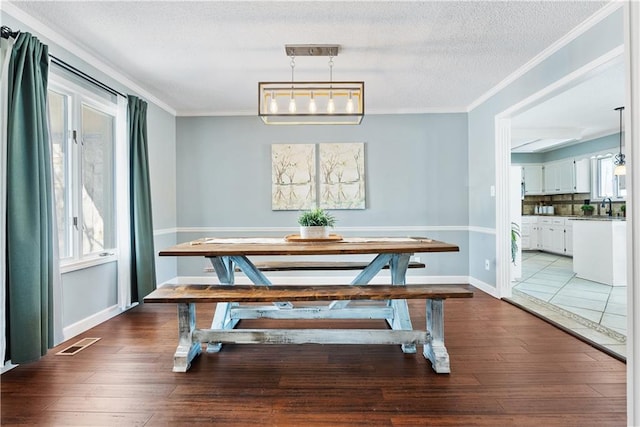 dining room with hardwood / wood-style floors, sink, ornamental molding, and a textured ceiling