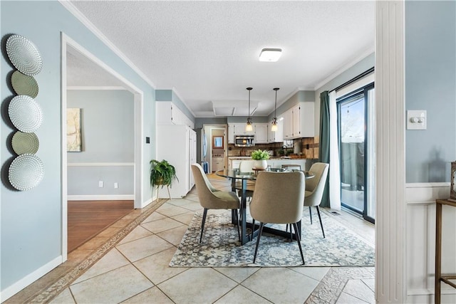 tiled dining room with a textured ceiling and ornamental molding