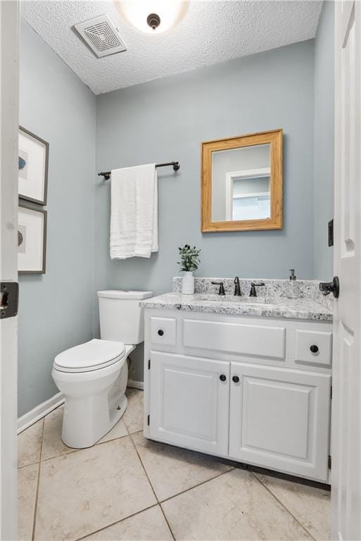 bathroom with tile patterned flooring, vanity, toilet, and a textured ceiling