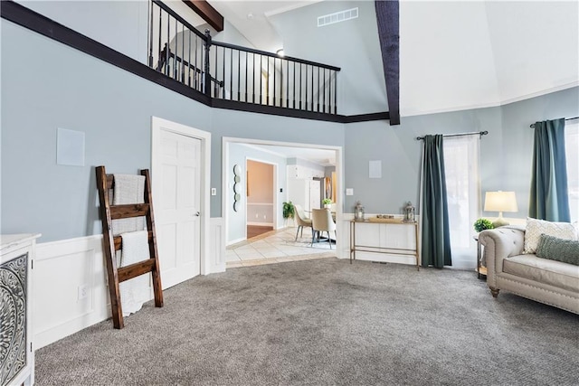 living room with beam ceiling, light colored carpet, and a high ceiling