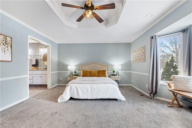 carpeted bedroom with ceiling fan, ornamental molding, connected bathroom, and a tray ceiling