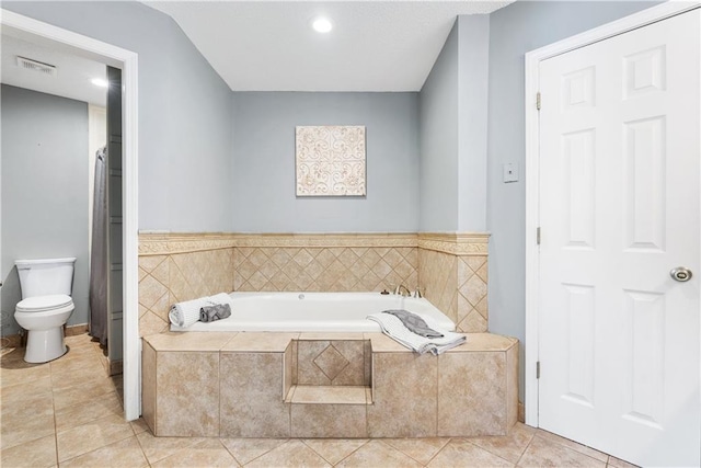 bathroom with tile patterned floors, toilet, and tiled tub