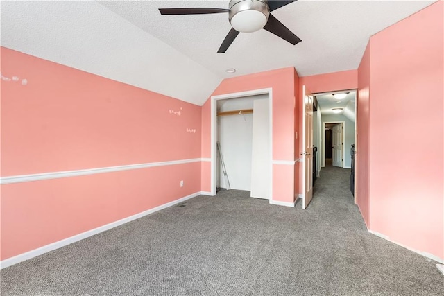 unfurnished bedroom featuring carpet, vaulted ceiling, a closet, and ceiling fan