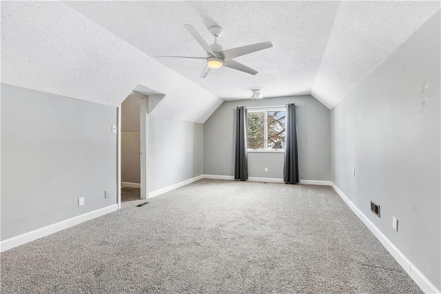 additional living space with a textured ceiling, light colored carpet, ceiling fan, and lofted ceiling