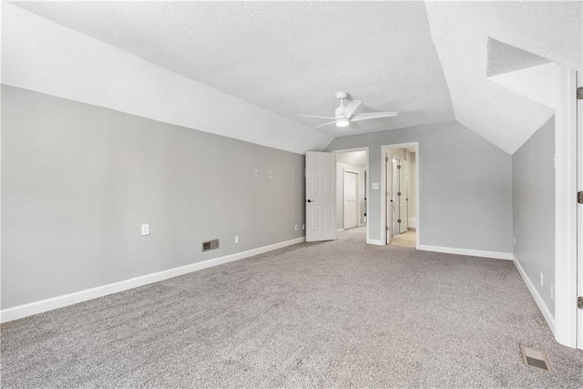 additional living space featuring vaulted ceiling, light carpet, ceiling fan, and a textured ceiling