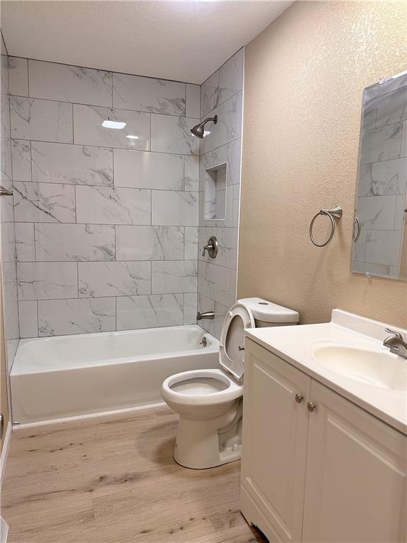 full bathroom featuring wood-type flooring, vanity, toilet, and tiled shower / bath