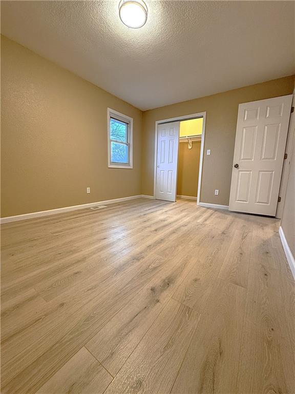 unfurnished bedroom featuring light wood-type flooring, a textured ceiling, and a closet