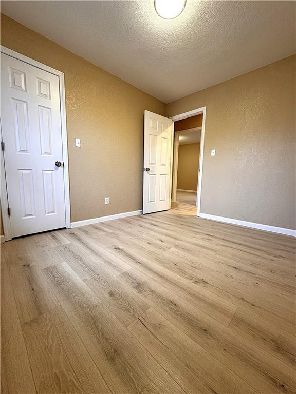 unfurnished room featuring a textured ceiling and light hardwood / wood-style floors