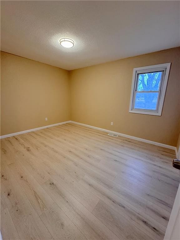 unfurnished room featuring light wood-type flooring and a textured ceiling