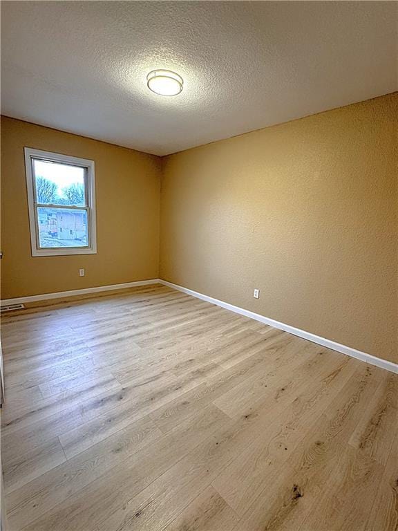 empty room with a textured ceiling and light wood-type flooring