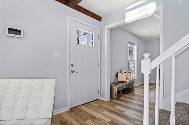 foyer entrance with a healthy amount of sunlight, light wood-type flooring, and beamed ceiling