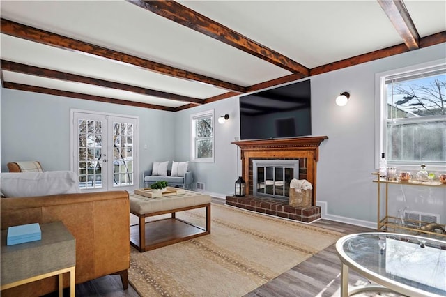 living room with french doors, a brick fireplace, beamed ceiling, and dark wood-type flooring