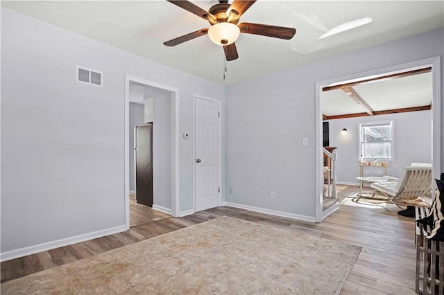 unfurnished room featuring light hardwood / wood-style floors, ceiling fan, and beamed ceiling