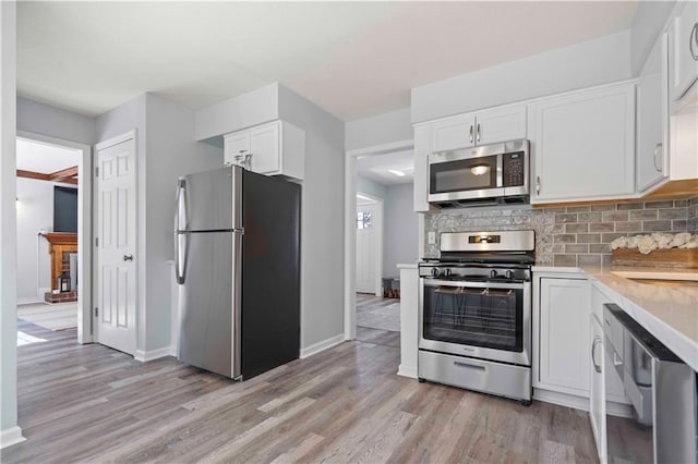 kitchen featuring light hardwood / wood-style flooring, stainless steel appliances, backsplash, white cabinetry, and sink