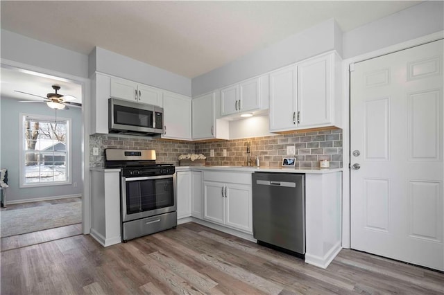 kitchen featuring appliances with stainless steel finishes, ceiling fan, white cabinetry, and backsplash