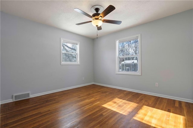 empty room featuring ceiling fan, a wealth of natural light, and dark hardwood / wood-style floors