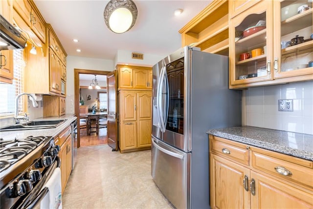 kitchen with backsplash, appliances with stainless steel finishes, sink, and dark stone counters