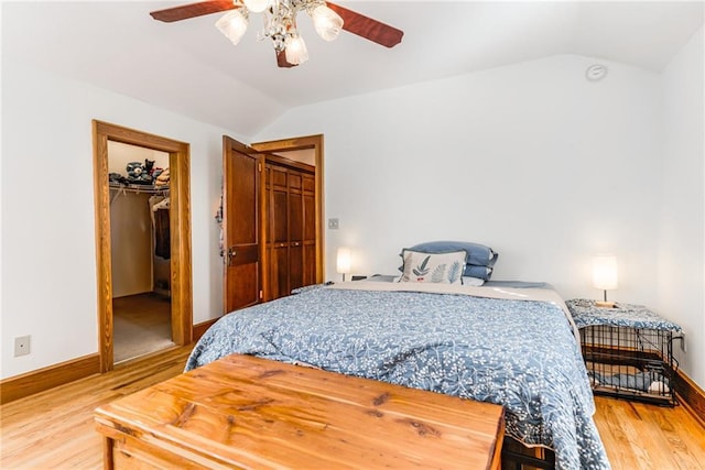 bedroom featuring lofted ceiling, hardwood / wood-style flooring, ceiling fan, a spacious closet, and a closet