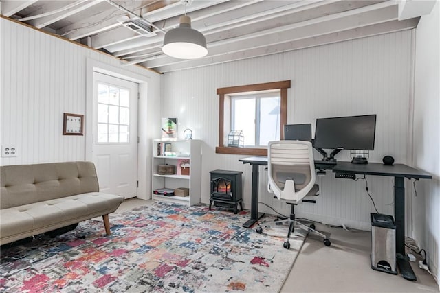 home office featuring plenty of natural light, concrete flooring, and a wood stove