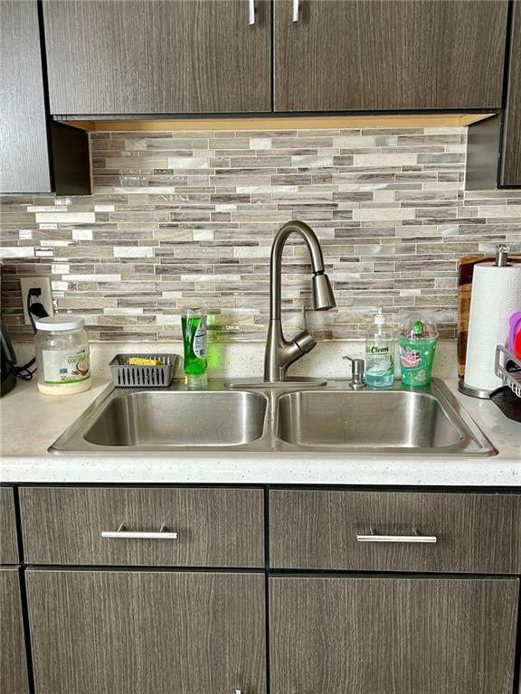 kitchen with dark brown cabinets, backsplash, and sink