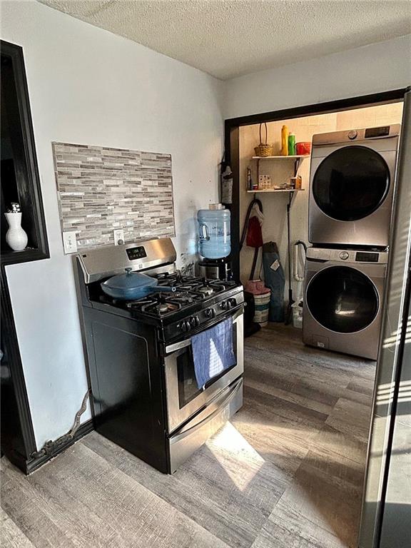 kitchen with stacked washer / dryer, stainless steel range with gas cooktop, hardwood / wood-style floors, and a textured ceiling