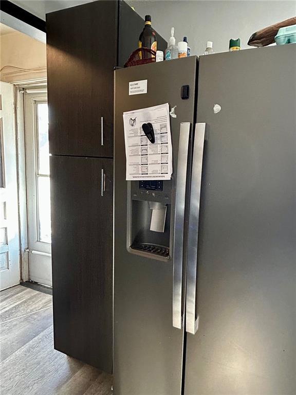 details with stainless steel refrigerator with ice dispenser and light hardwood / wood-style flooring