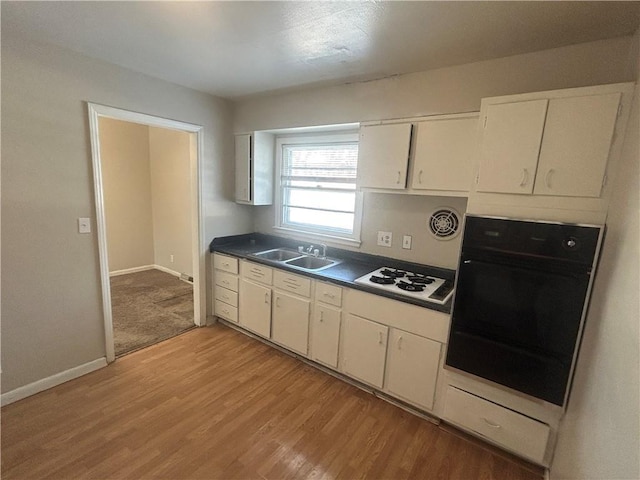 kitchen with sink, white gas stovetop, light hardwood / wood-style flooring, oven, and white cabinets