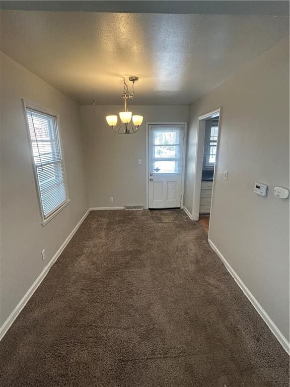 interior space with dark colored carpet and an inviting chandelier