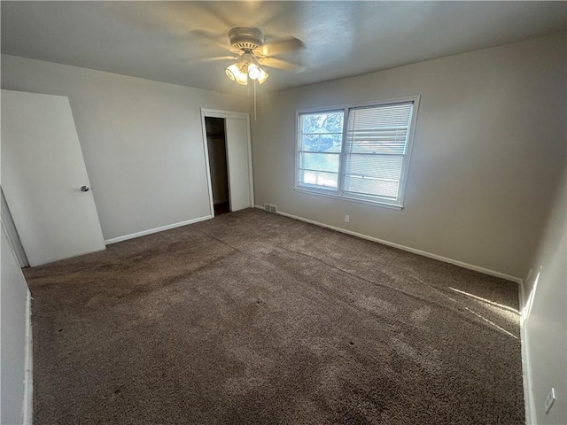 unfurnished bedroom with dark colored carpet, ceiling fan, and a closet