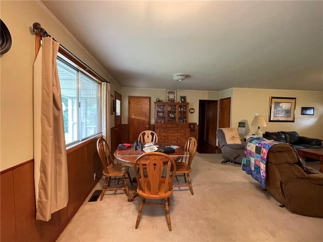 dining area featuring wood walls and light colored carpet