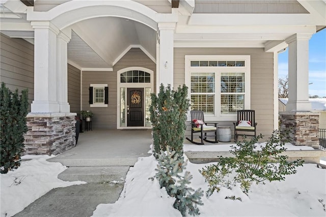 snow covered property entrance featuring a porch