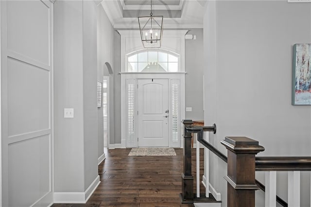 entrance foyer featuring dark hardwood / wood-style flooring, crown molding, and an inviting chandelier