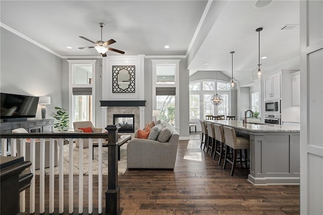 living room featuring a fireplace, sink, dark hardwood / wood-style floors, ceiling fan, and crown molding