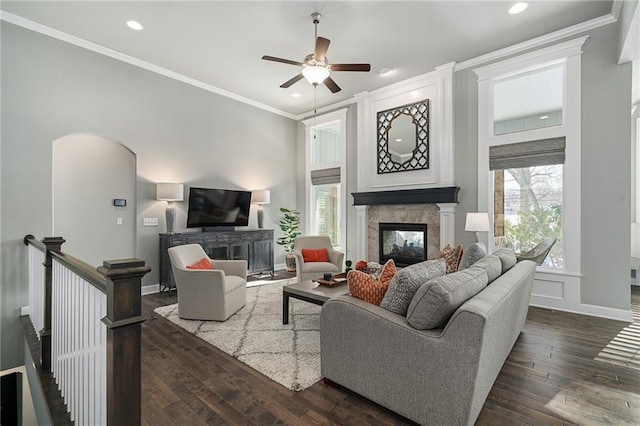 living room with dark wood-type flooring, ornamental molding, a multi sided fireplace, and ceiling fan