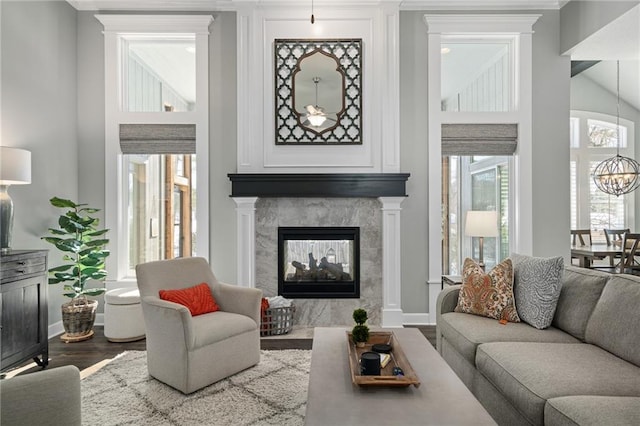 living room with a healthy amount of sunlight, wood-type flooring, a notable chandelier, and a multi sided fireplace