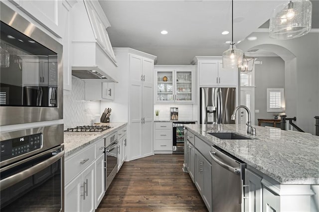 kitchen featuring a kitchen island with sink, pendant lighting, stainless steel appliances, and white cabinetry