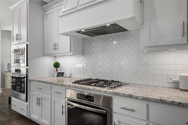 kitchen featuring appliances with stainless steel finishes, custom exhaust hood, white cabinets, and tasteful backsplash