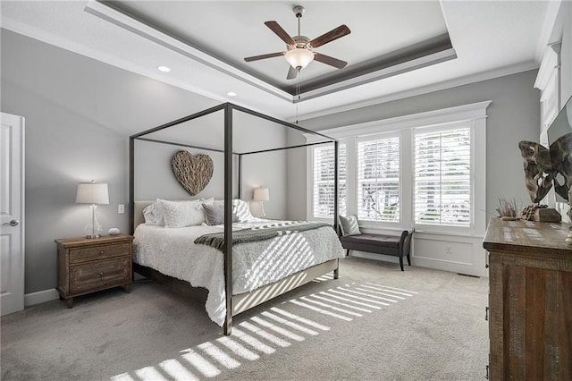 bedroom featuring ceiling fan, light carpet, a tray ceiling, and ornamental molding