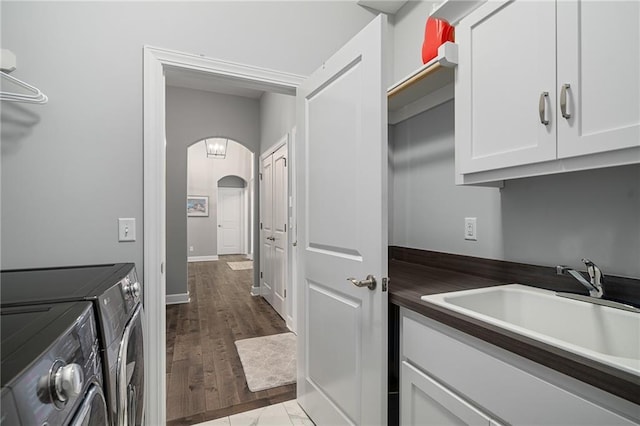 laundry area with cabinets, separate washer and dryer, light hardwood / wood-style flooring, and sink