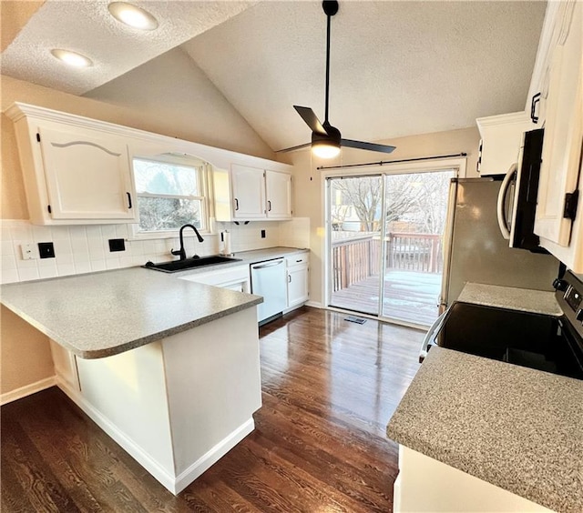 kitchen with appliances with stainless steel finishes, kitchen peninsula, sink, and white cabinets