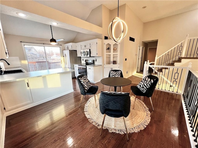 dining space featuring dark wood-type flooring, ceiling fan, high vaulted ceiling, and sink