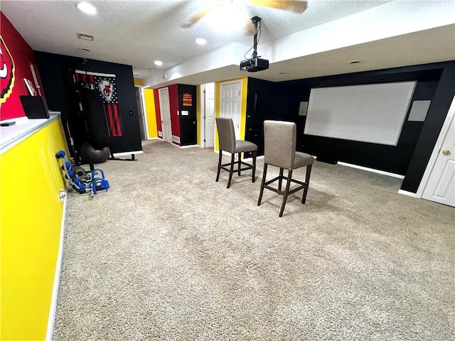 cinema with ceiling fan, carpet flooring, and a textured ceiling