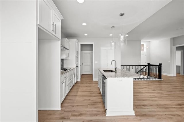 kitchen with sink, white cabinetry, hanging light fixtures, stainless steel appliances, and light stone counters