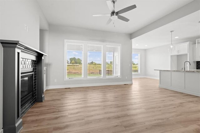 5005 146th St, Basehor, KS 66007 - unfurnished living room featuring light wood-type flooring, recessed lighting, ceiling fan, and a fireplace
